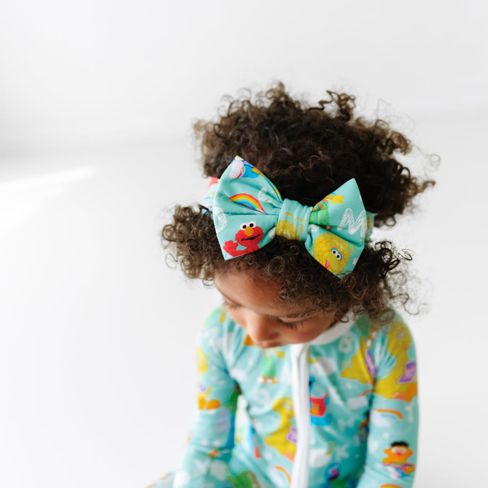 Alternate overhead image of a child wearing a Spelling with Sesame Street luxe bow headband