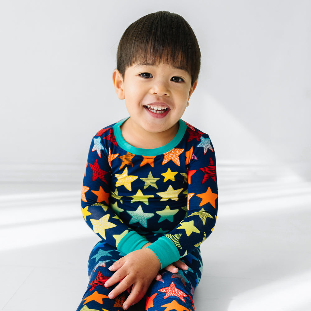 Click to see full screen - Close up image of a child sitting wearing a Shades of Stars two piece pajama set