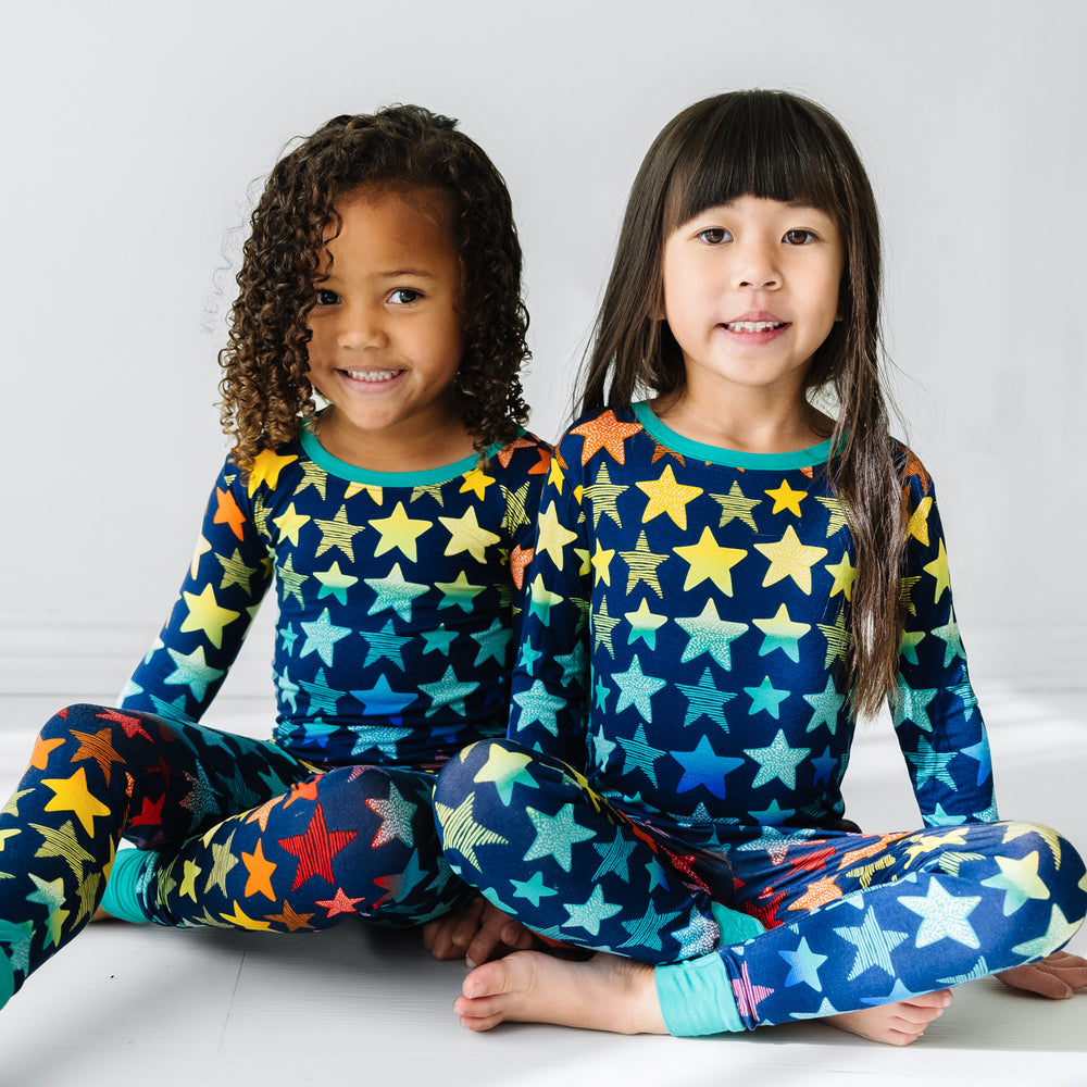 Click to see full screen - Two children sitting wearing Shades of Stars two piece pajama sets