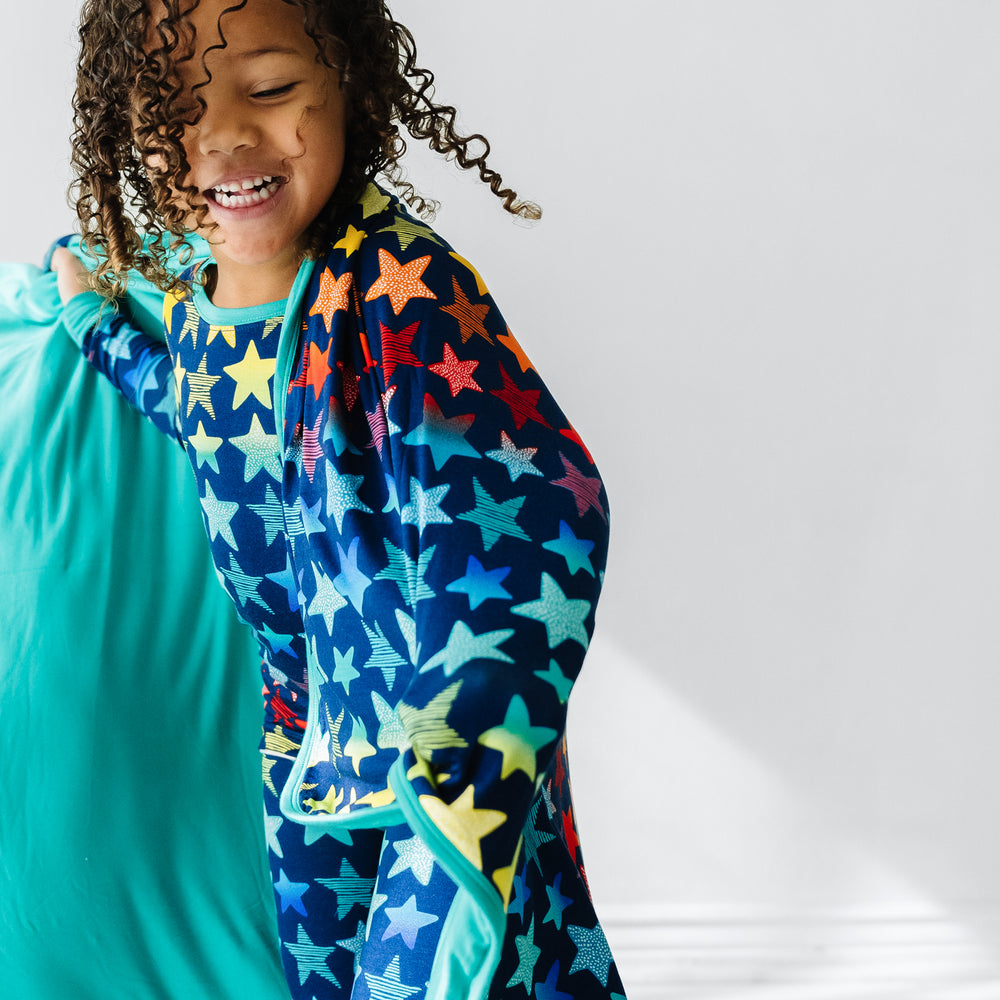 Click to see full screen - Close up image of a child wearing a Shades of Stars two piece pajama set with a matching large cloud blanket over her shoulders 