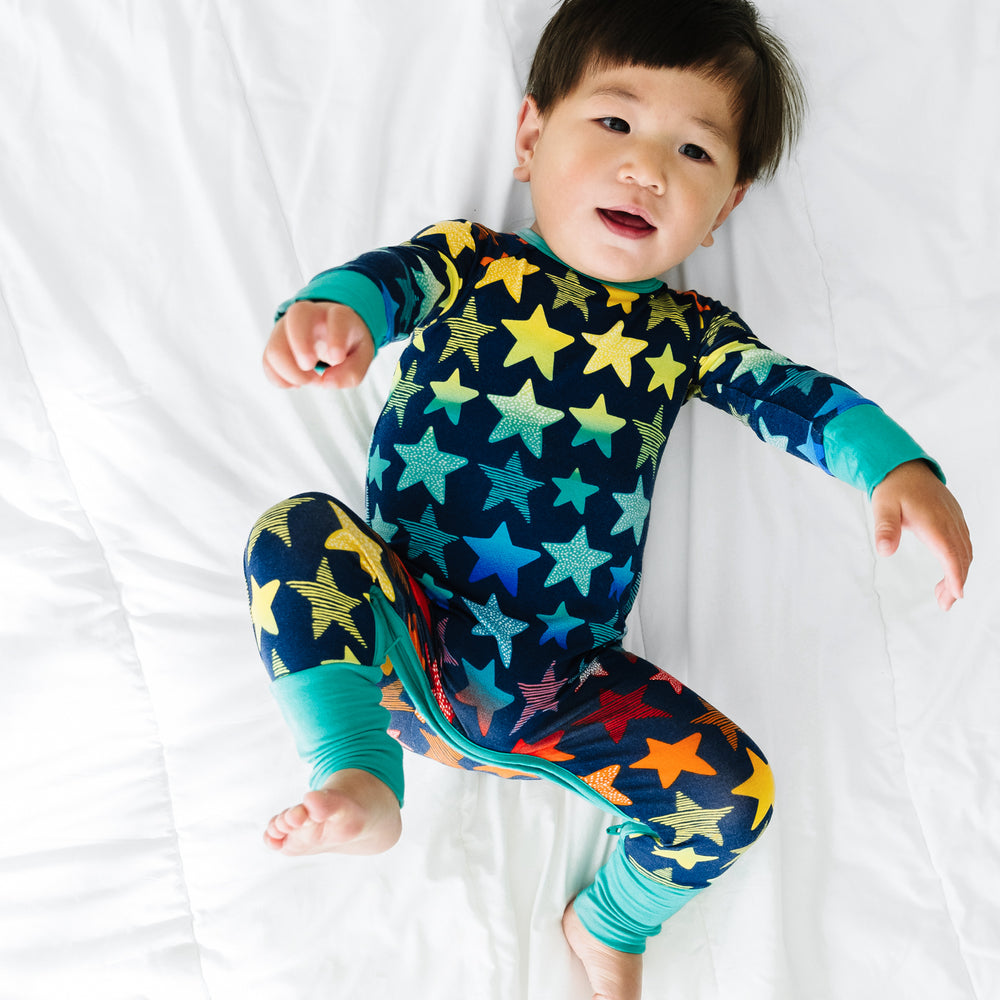 Child laying on a bed wearing a Shades of Stars crescent zippy