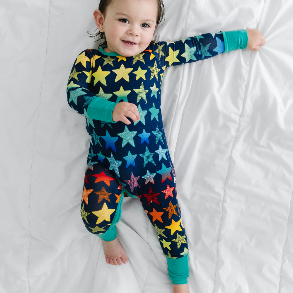 Click to see full screen - alternate image of a child laying on a bed wearing a Shades of Stars crescent zippy
