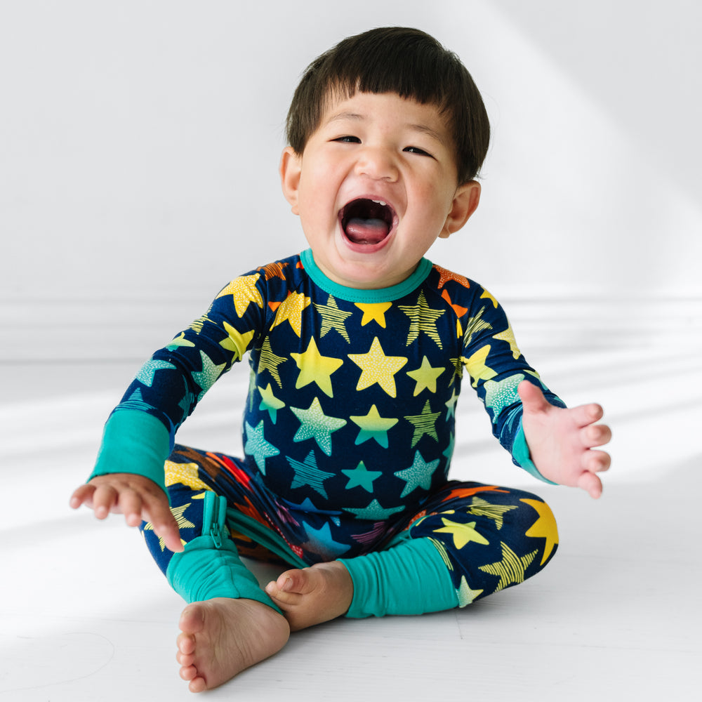 Click to see full screen - Child sitting on a bed wearing a Shades of Stars crescent zippy