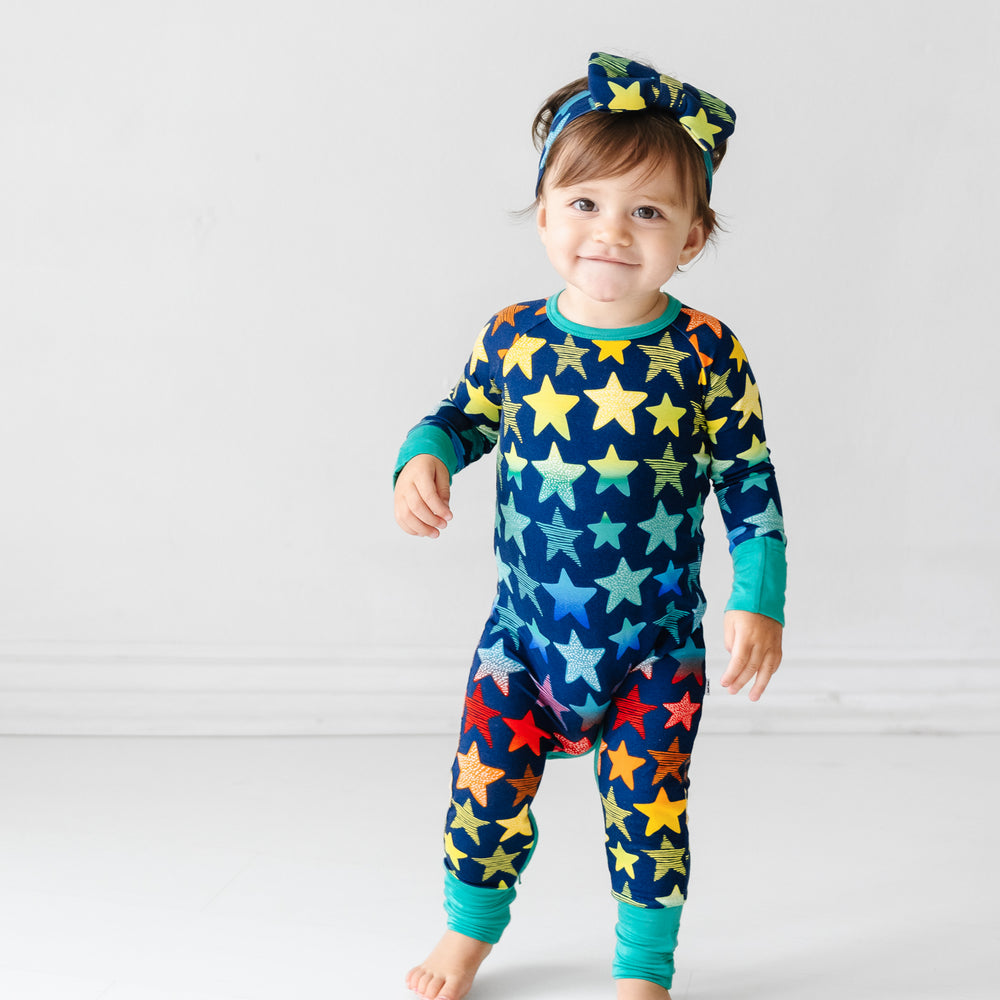 Click to see full screen - Child wearing a Shades of Stars crescent zippy paired with a matching luxe bow headband