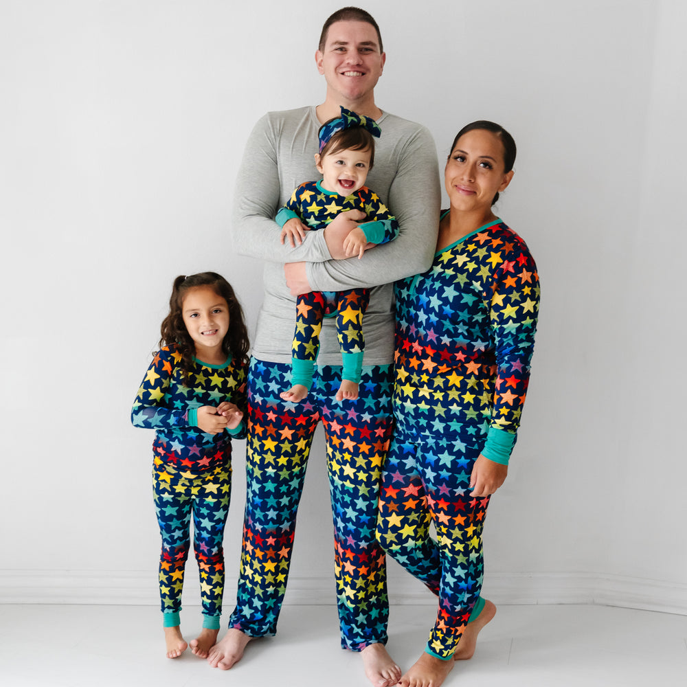 Click to see full screen - Family of four matching wearing Shades of Stars pajamas. Dad is wearing Shades of Stars men's pajama pants paired with a Heather Gray men's pajama top. Mom is wearing Shades of Stars women's pajama top paired with women's pajama pants. Their children are wearing Shades of Stars two piece and crescent zippy pajamas