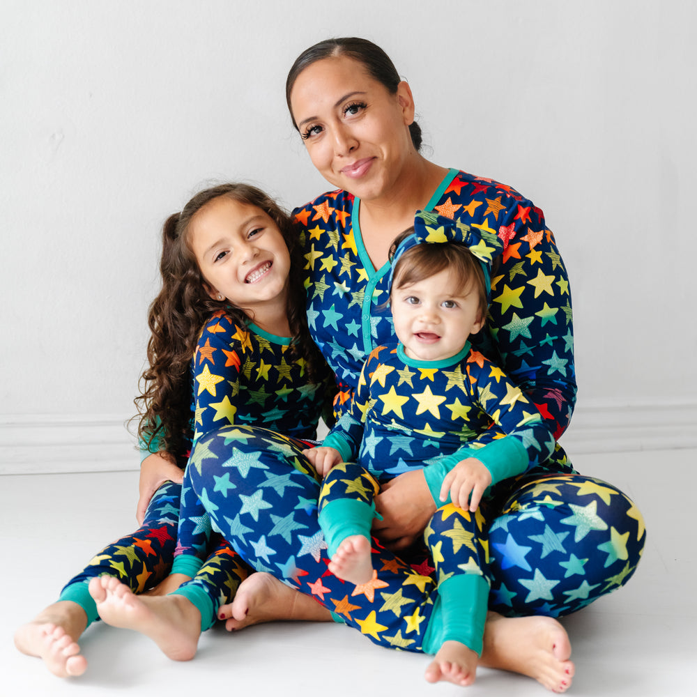 Click to see full screen - Mother and her two children matching wearing Shades of Stars pajamas. Mom is wearing Shades of Stars women's pajama pants paired with a matching women's pajama top. Her children are wearing Shades of Stars two piece and crescent zippy pajamas