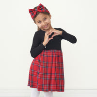 Child wearing a Holiday Plaid skater dress and matching luxe bow headband