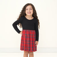 Child with a hand on her hip wearing a Holiday Plaid skater dress