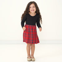 Child jumping wearing a Holiday Plaid skater dress