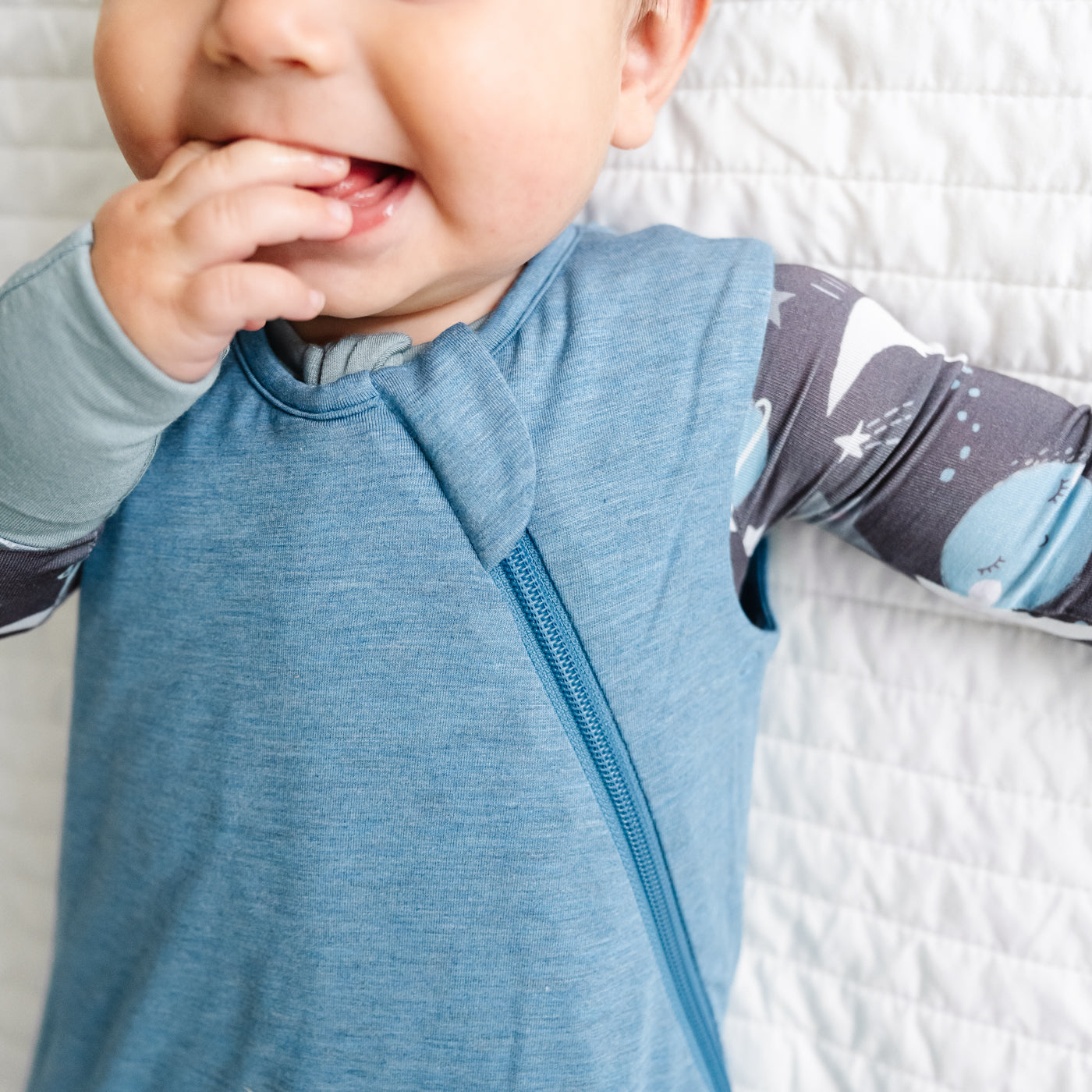 Close up image of a child wearing a Heather Blue Sleepy Bag and coordinating zippy