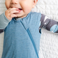 Close up image of a child wearing a Heather Blue Sleepy Bag and coordinating zippy
