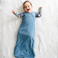 Alternate image of a child laying on a blanket wearing a Heather Blue Sleepy Bag and coordinating zippy