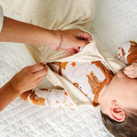 Child wearing a Heather Oatmeal sleepy bag with a parent zipping it up