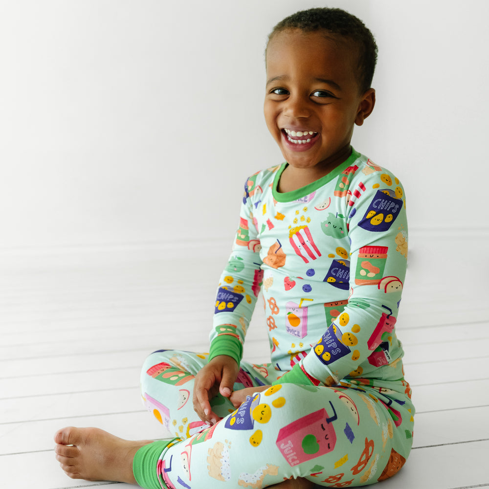 Child sitting wearing a Snack Attack two piece pajama set