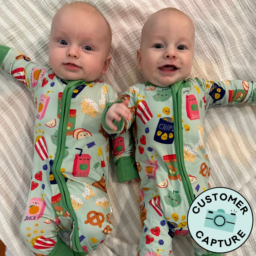 Customer Capture image of a two children laying on a bed wearing matching Snack Attack zippies