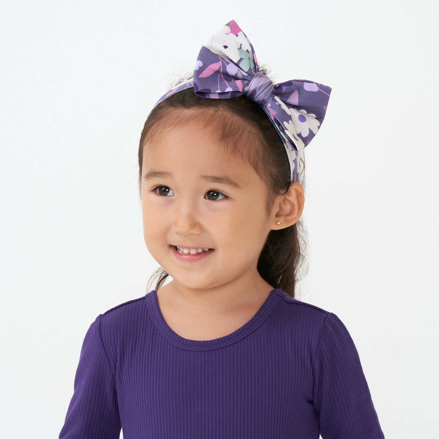 Alternate close up image of a child wearing a Sugar Plum Floral luxe bow headband paired with a Deep Amethyst cozy lettuce tee