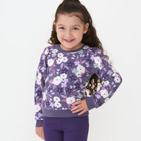Child posing wearing a Sugar Plum Floral puff sleeve crewneck paired with Deep Amethyst cozy lettuce legging