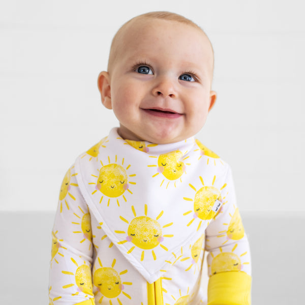 Close up of a child wearing a Sunshine Bandana Bib over matching Sunshine bamboo pajamas