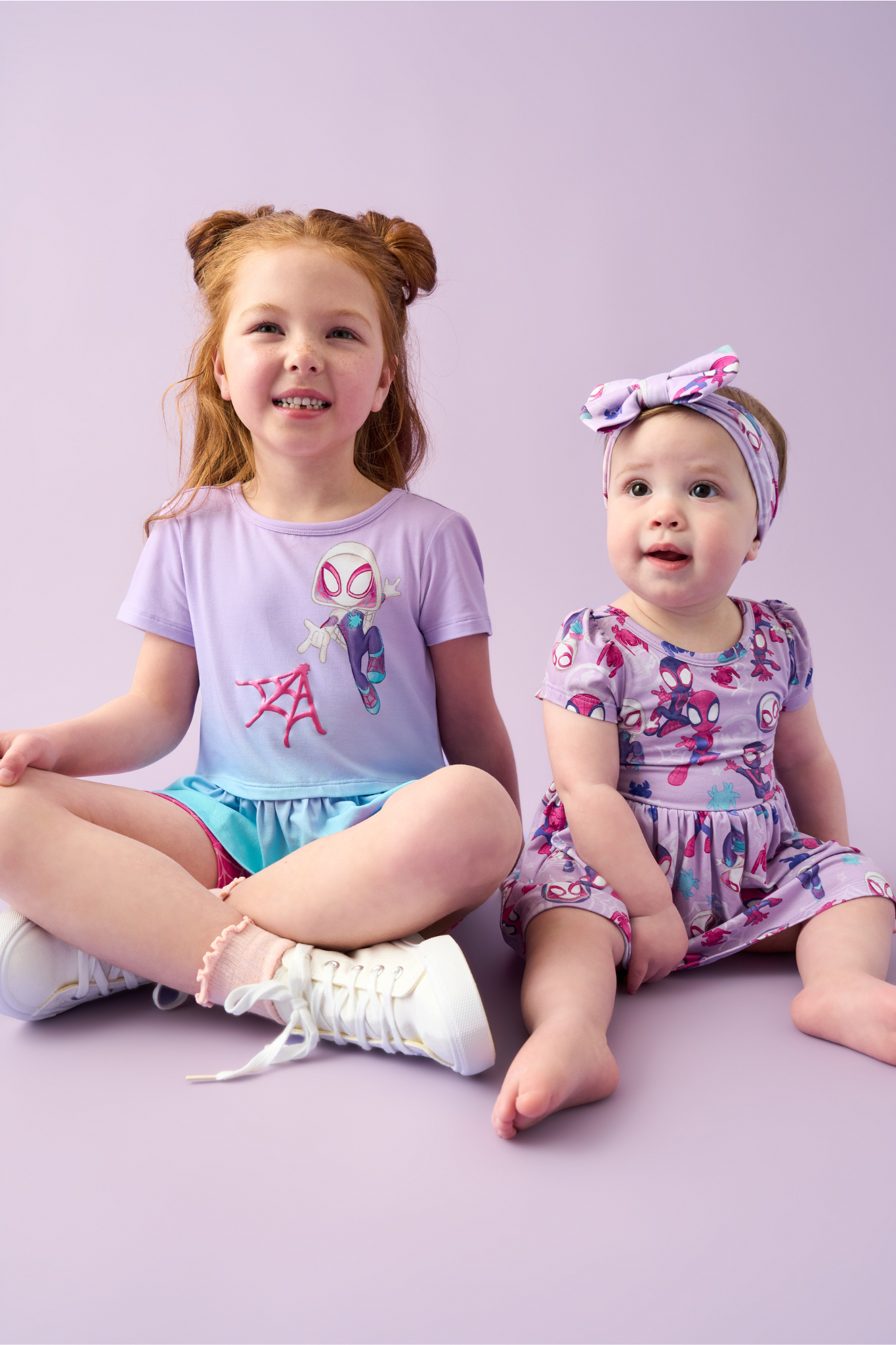 Two children sitting on the ground wearing Spidey & His Amazing Friends clothes
