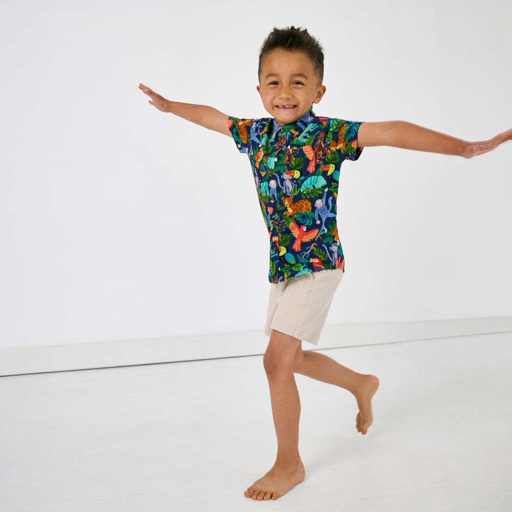 Posing child wearing the Treetop Tails Button Down Polo with light khaki shorts