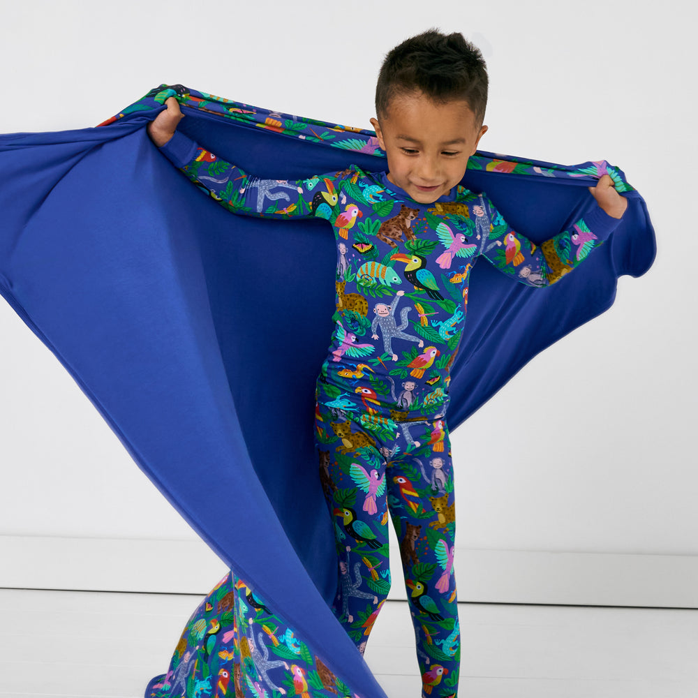 Child wearing the Treetop Tails PJ Set hold up the Large Cloud Blanket®