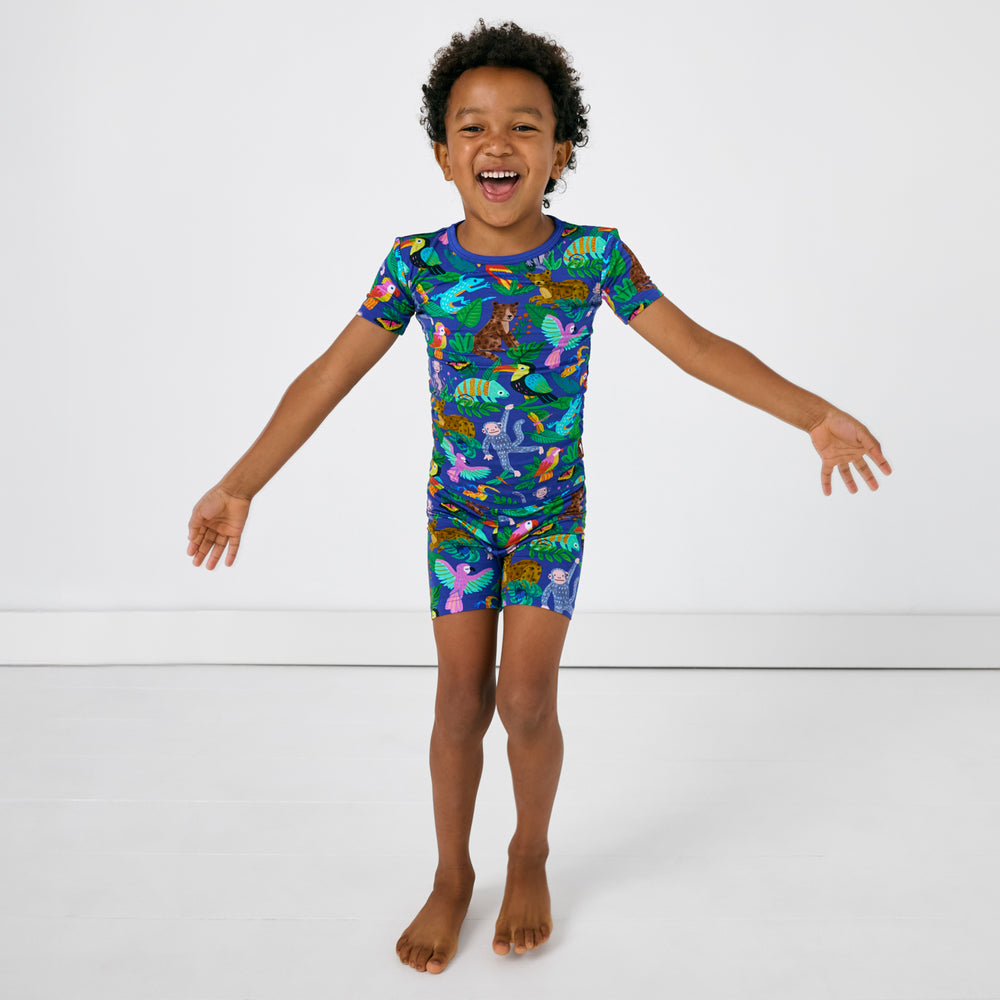Standing child wearing the Treetop Tails Two-Piece Short Sleeve & Shorts Pajama Set