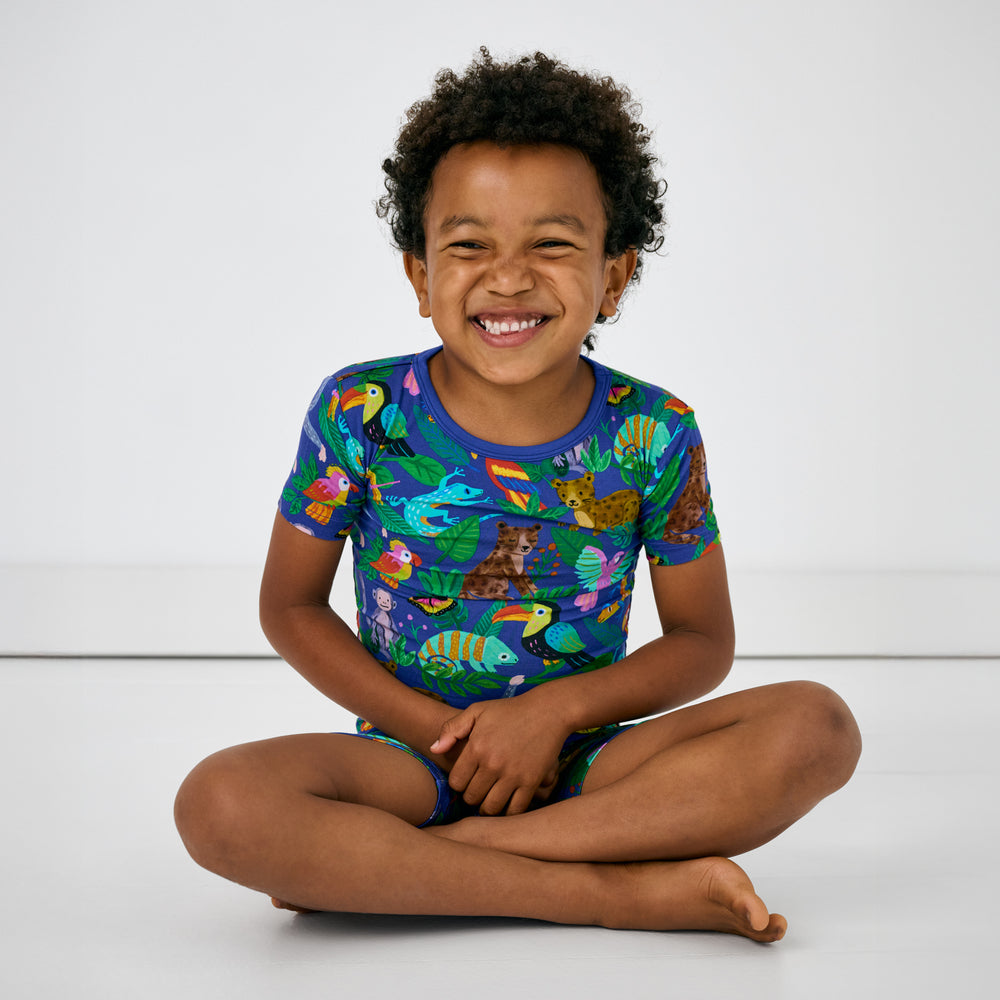 Sitting child wearing the Treetop Tails Two-Piece Short Sleeve & Shorts Pajama Set