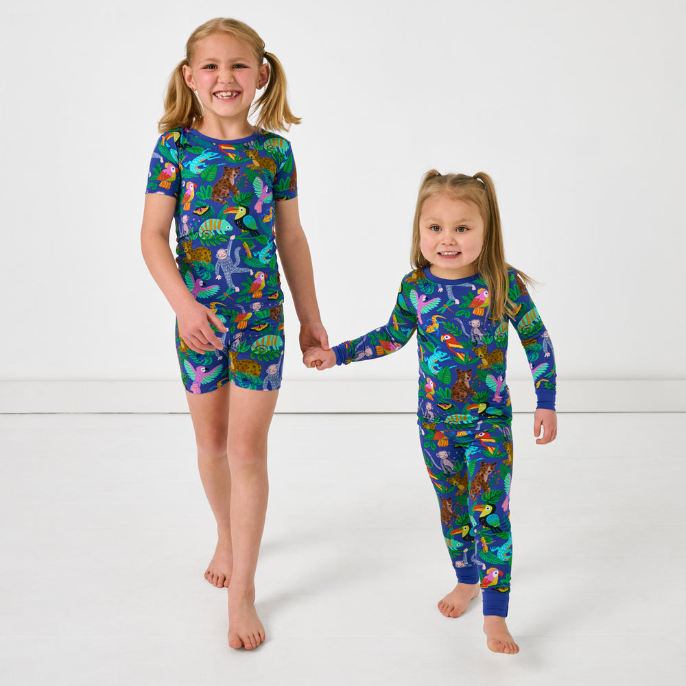 Two children holding hands wearing matching Treetop Tails Two-Piece Bamboo Pajama Sets