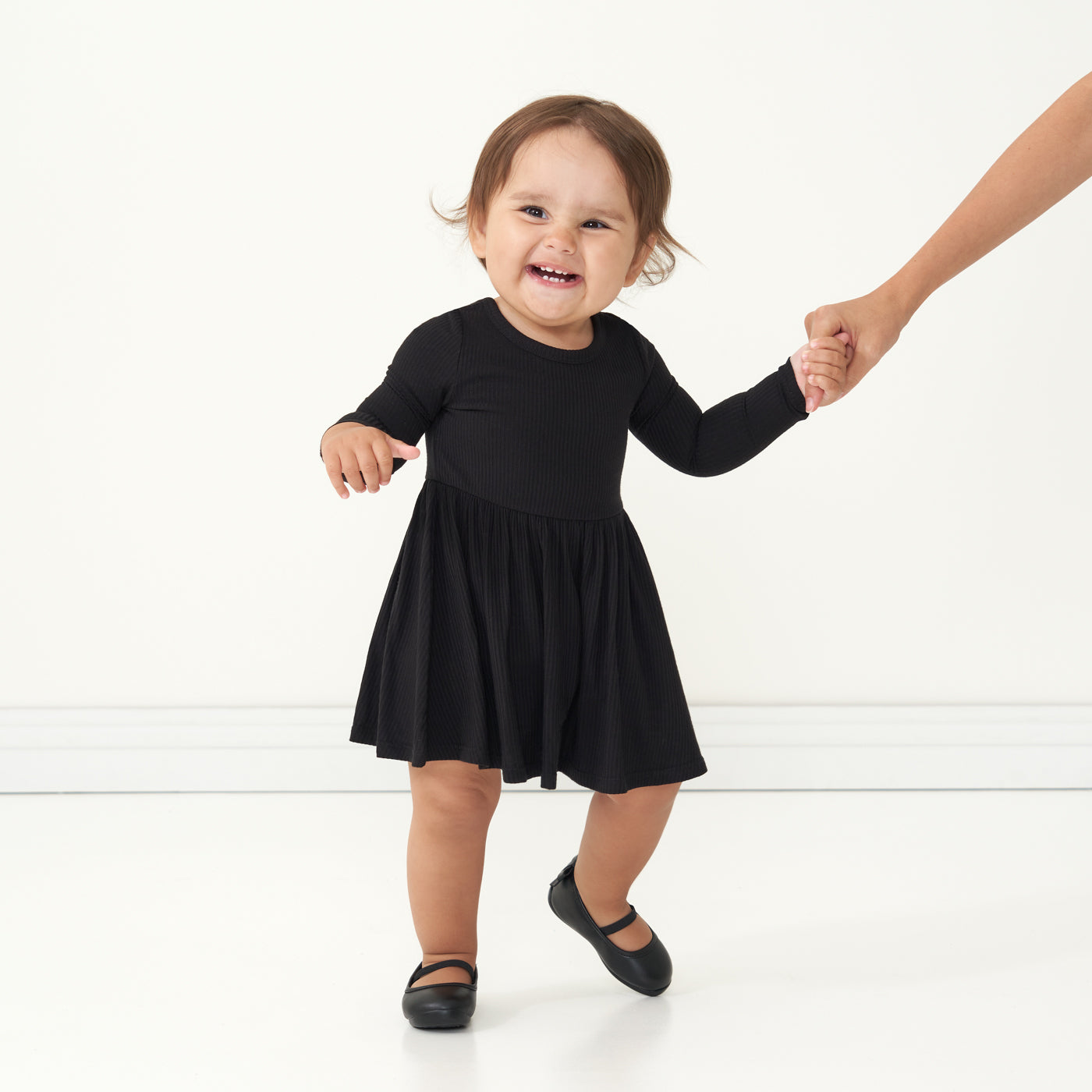 Child holding a parent's hand wearing a Black ribbed twirl dress with bodysuit