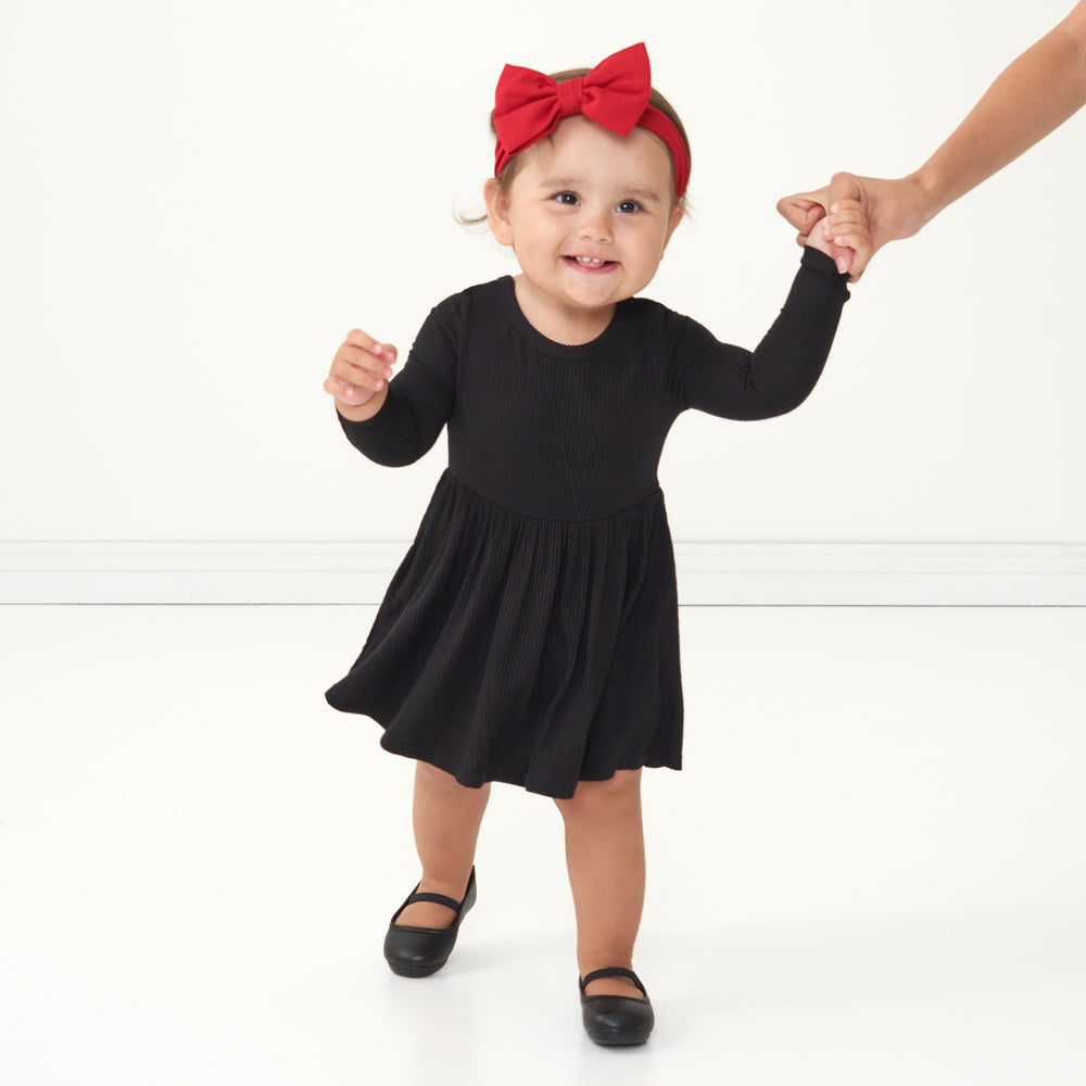 Child wearing a Black ribbed twirl dress with bodysuit and coordinating Holiday Red luxe bow headband