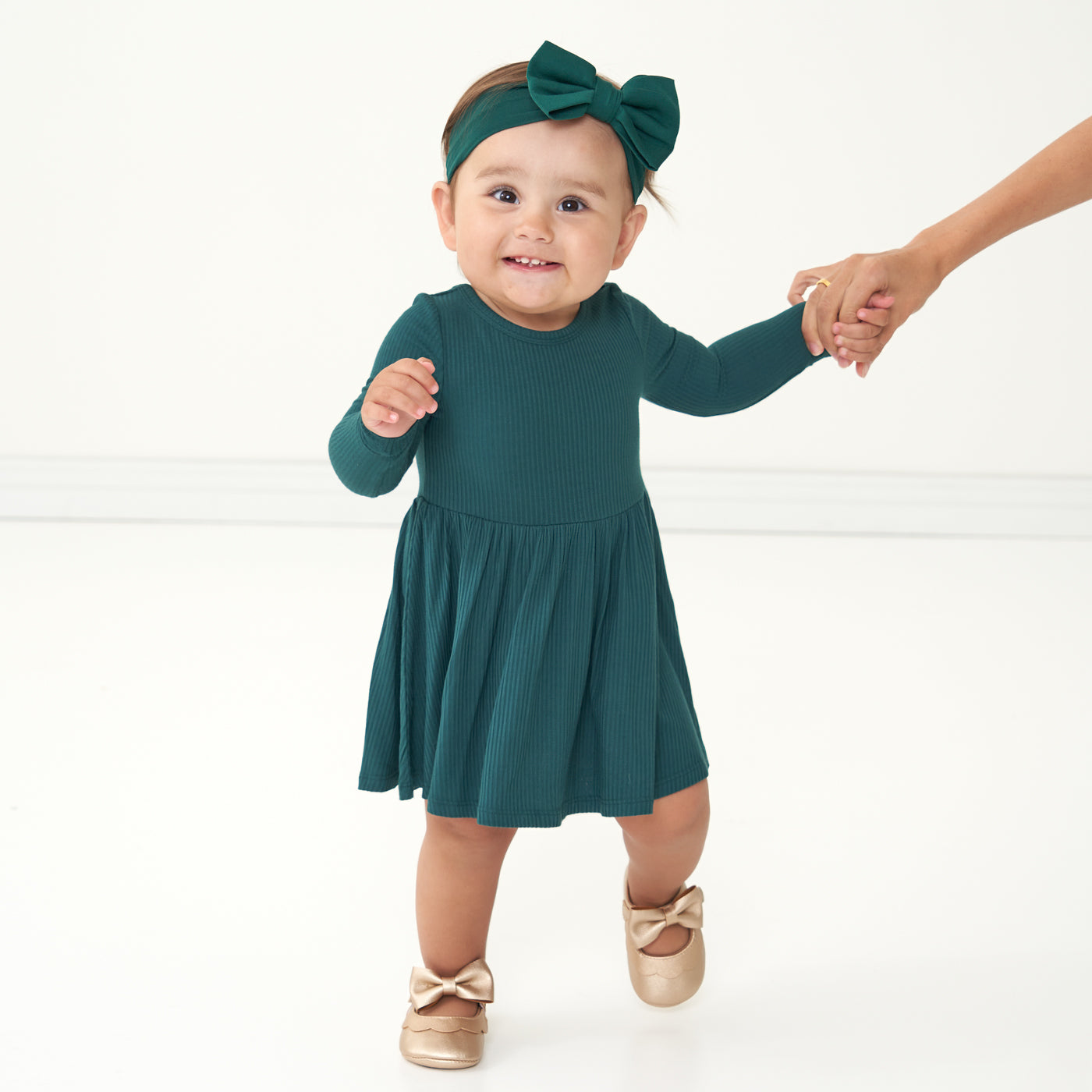 Child wearing an emerald ribbed twirl dress with bodysuit paired with an Emerald luxe bow headband