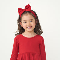 child wearing a ribbed twirl dress paired with a Holiday Red luxe bow headband