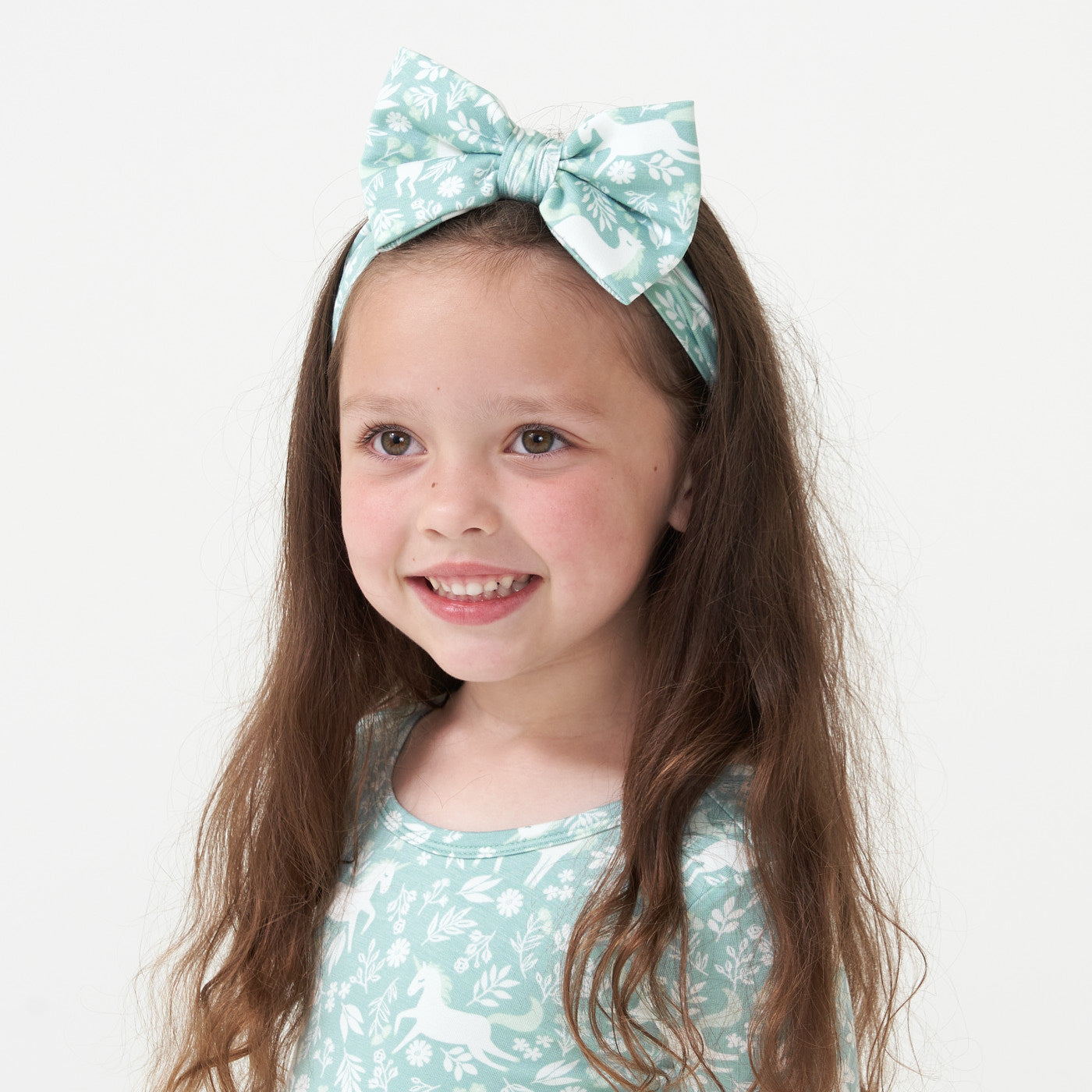 Close up image of a child wearing a Unicorn Garden luxe bow headband