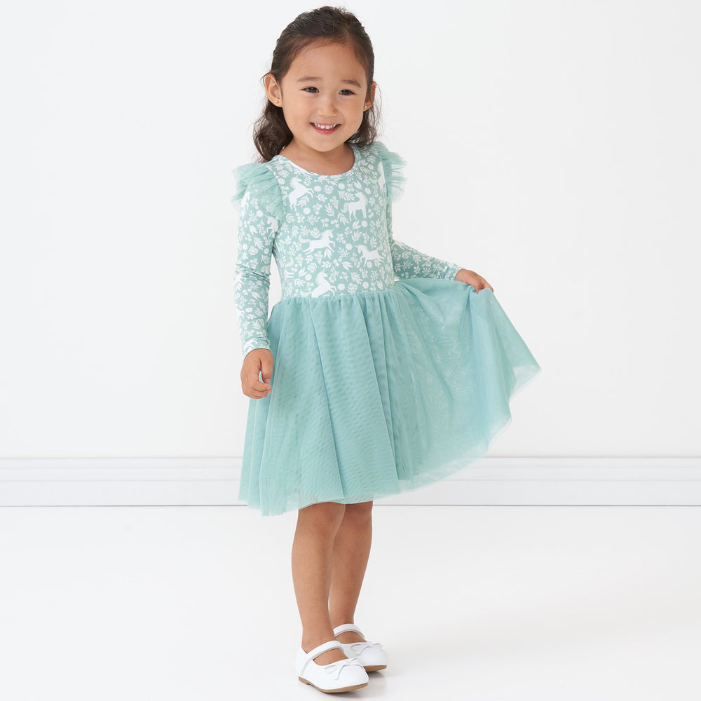 Child holding up the side of her dress wearing a Unicorn Garden flutter tutu dress