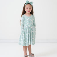 Child wearing a Unicorn Garden twirl dress and coordinating Aqua Mist luxe bow headband