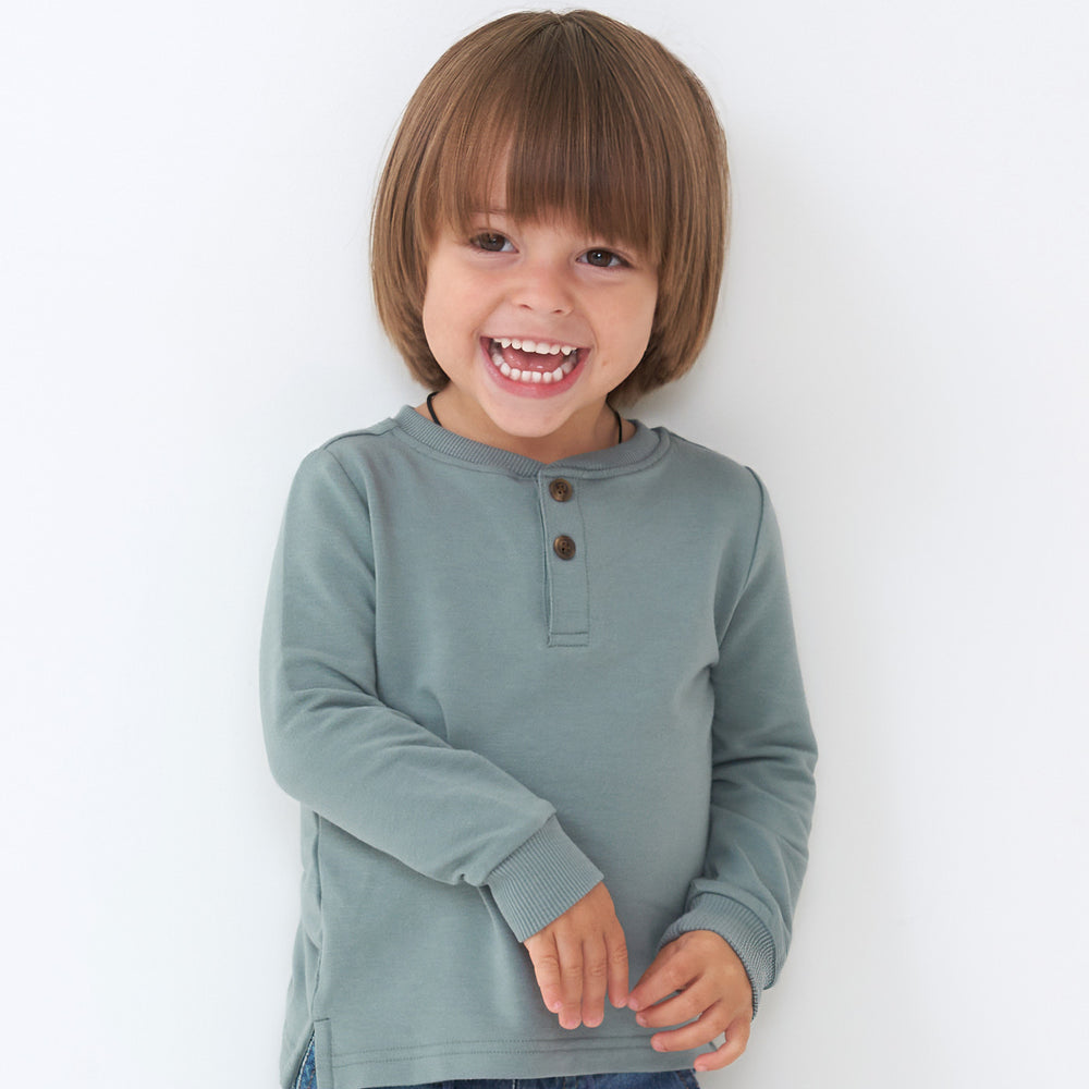Close up image of a child wearing a Vintage Teal henley tee