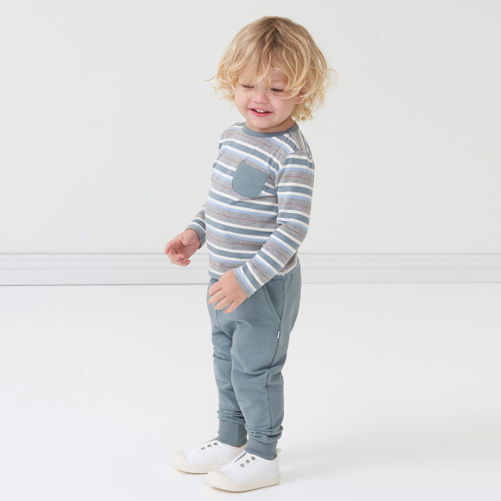 Side view image of a child wearing a Vintage Teal Stripes pocket tee and coordinating Vintage Teal joggers