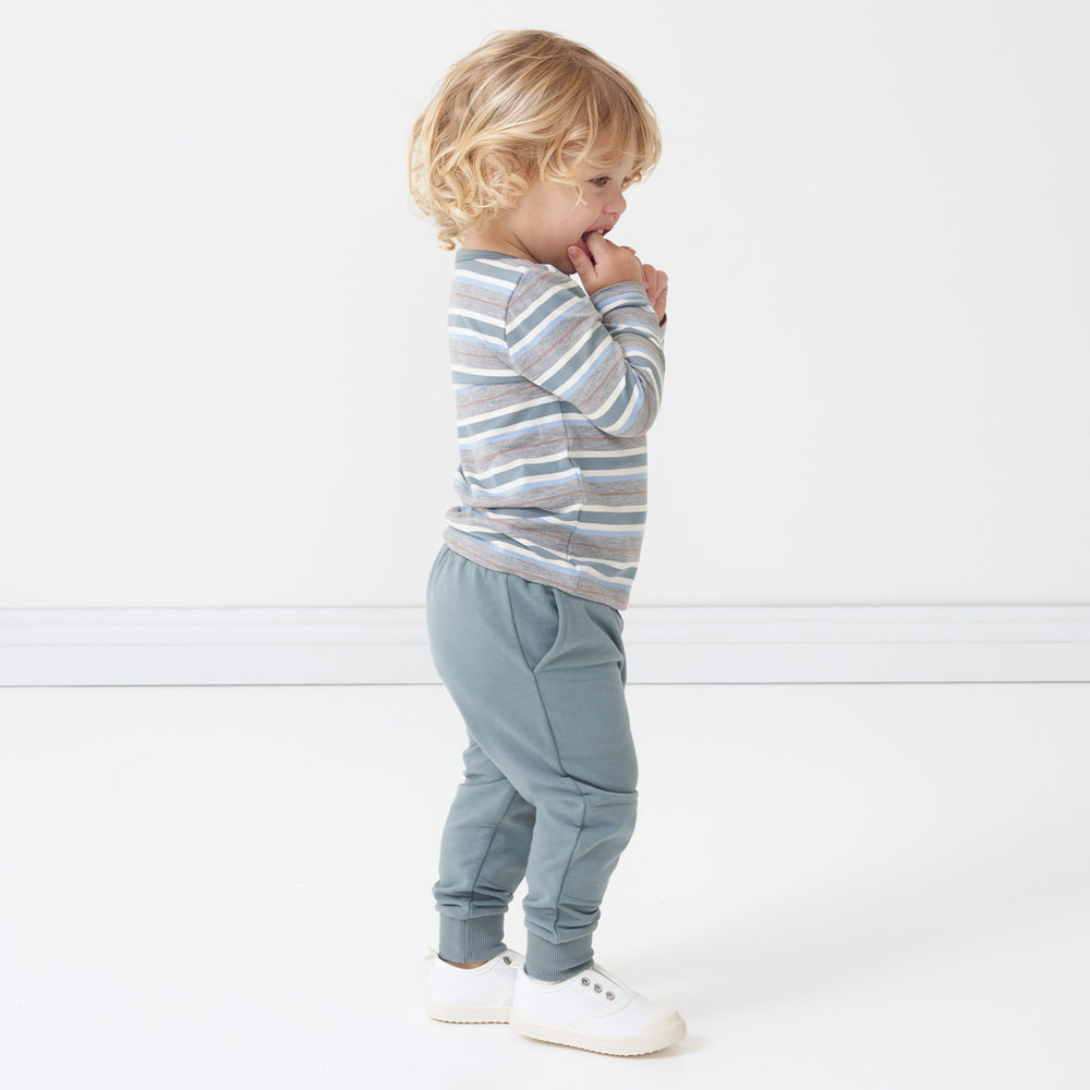 Alternate side view image of a child wearing a Vintage Teal Stripes pocket tee and coordinating Vintage Teal joggers