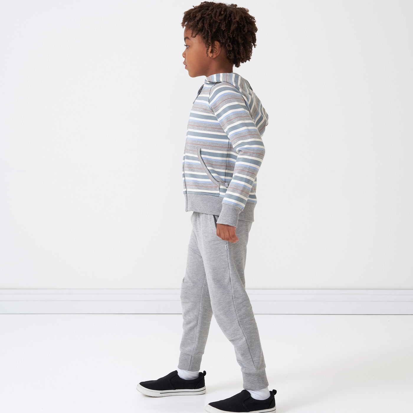 Side view image of a child wearing a Vintage Teal Stripes zip hoodie and coordinating Heather Gray joggers