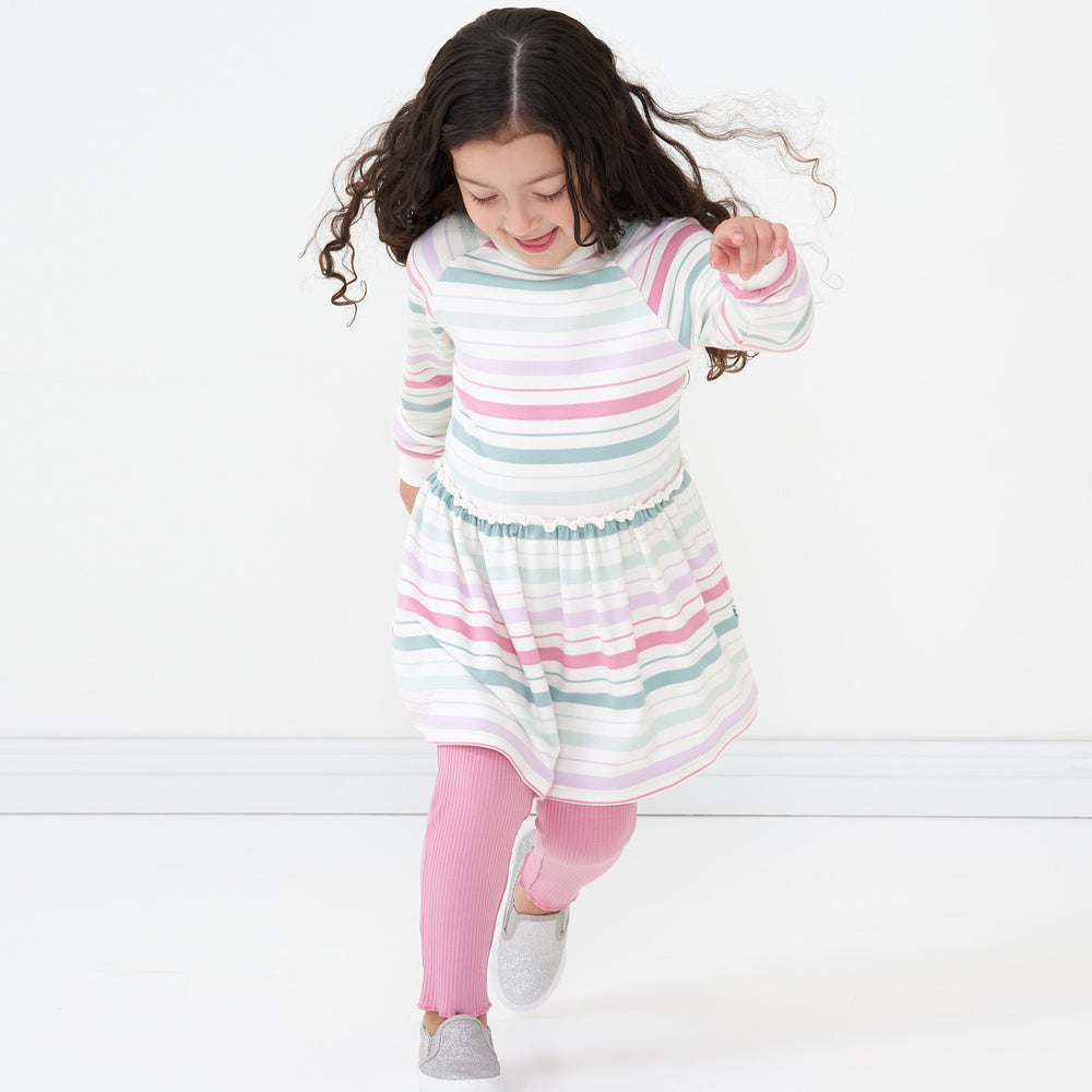 Child running wearing Winter Stripes drop waist dress paired with Garden Rose lettuce leggings