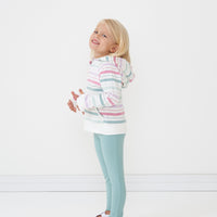 Profile view of a child wearing a Winter Stripes zip hoodie paired with Aqua Mist lettuce leggings