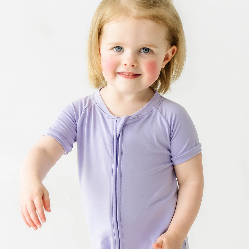 Close up image of a child wearing a Wisteria shorty romper