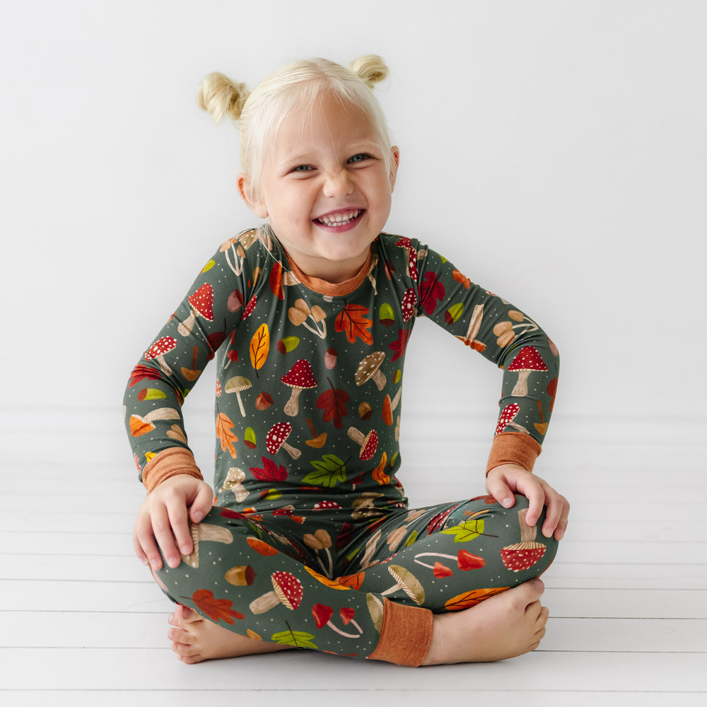 Child sitting on the ground wearing a Woodland Forest two-piece pajama set