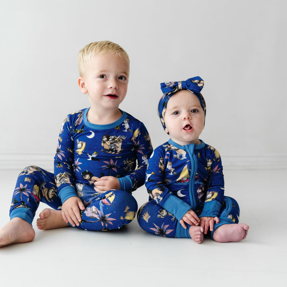 Two children wearing matching Where the Wild Things Are pajama sets and matching luxe bow headband