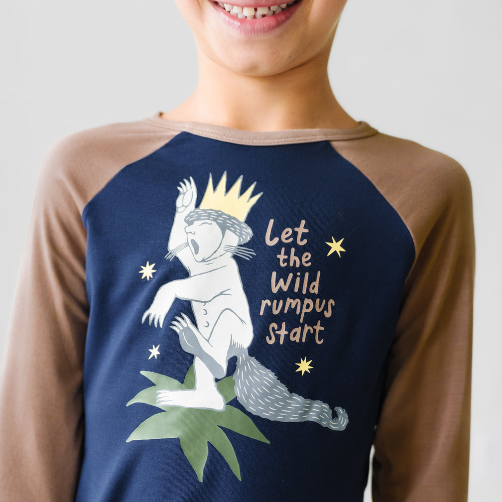 Close up image of a child wearing a Where the Wild Things Are graphic raglan tee