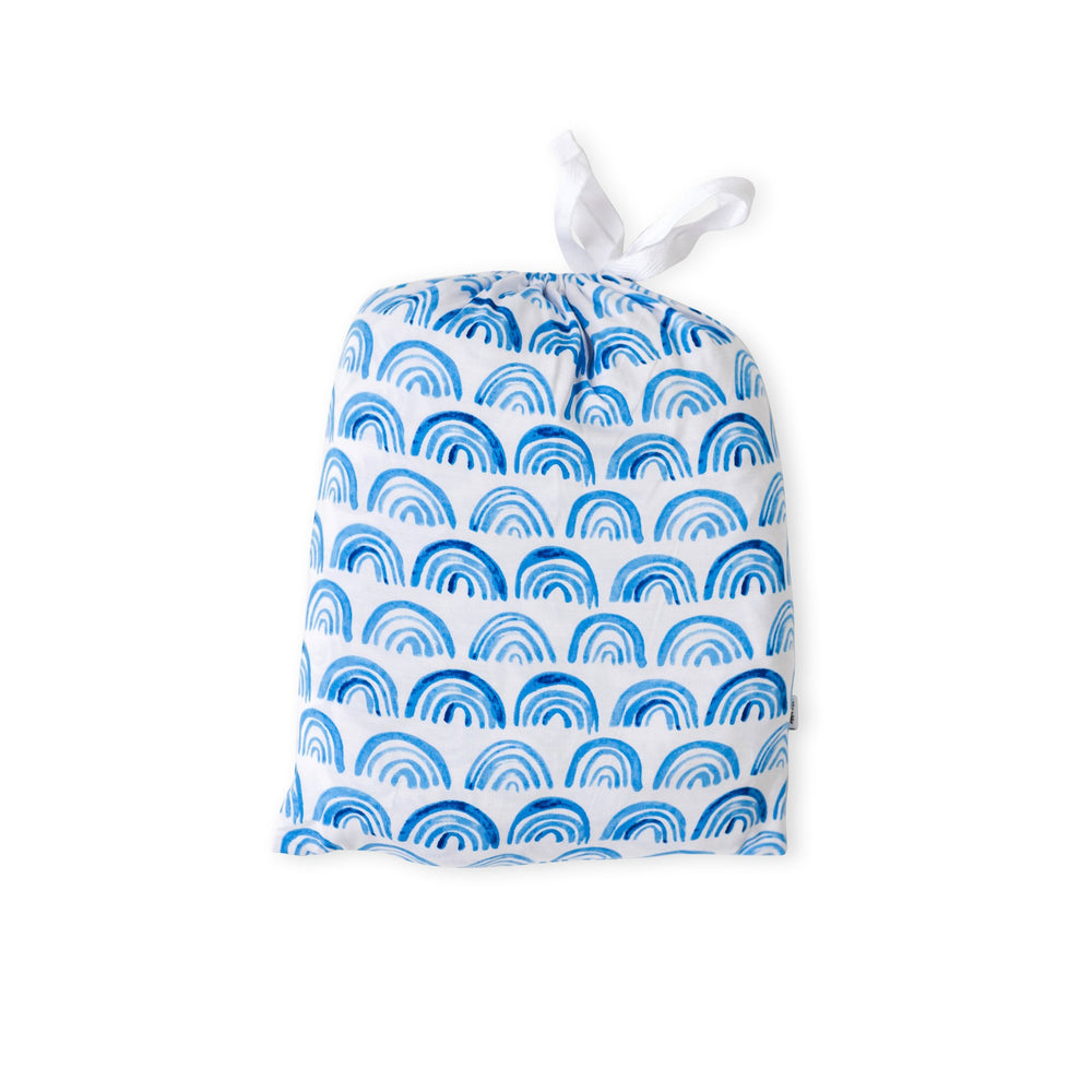 Reusable Blue Rainbows drawstring bag containing a standard fitted crib sheet in Blue Rainbows print