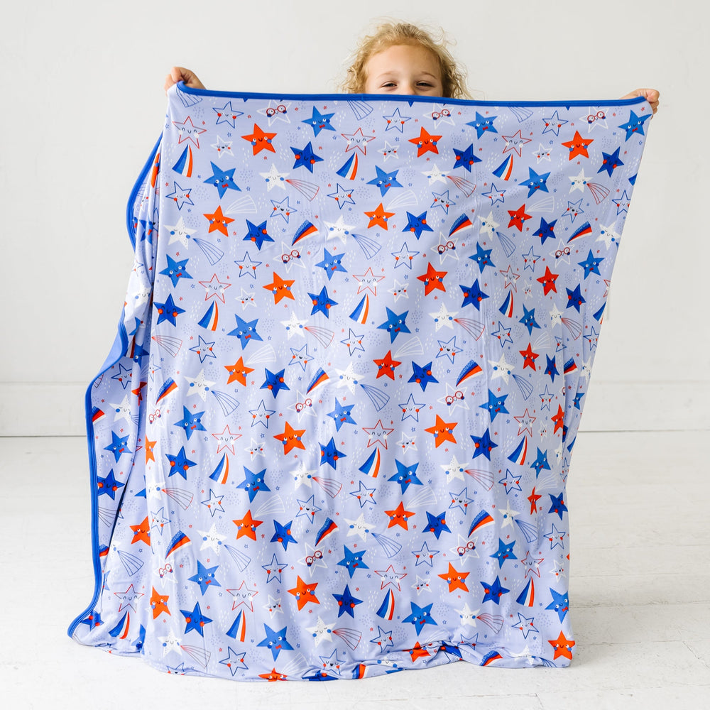 Child holding up a Blue Stars and Stripes Cloud Blanket