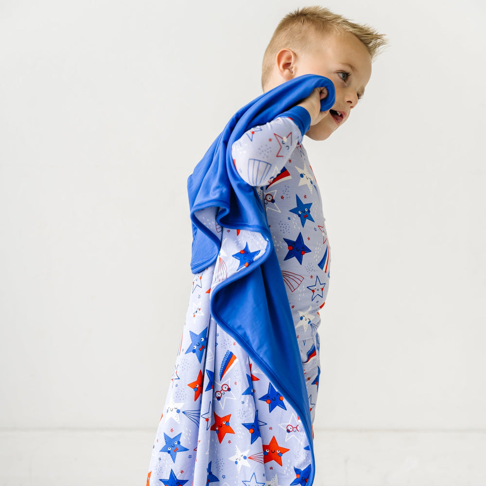 Child wearing a Blue Stars and Stripes Cloud Blanket on his shoulders that matches his Blue Stars and Stripes printed two piece pajama set