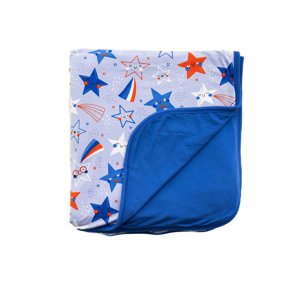Flat lay image of a Blue Stars and Stripes printed cloud blanket showing off the solid blue backing