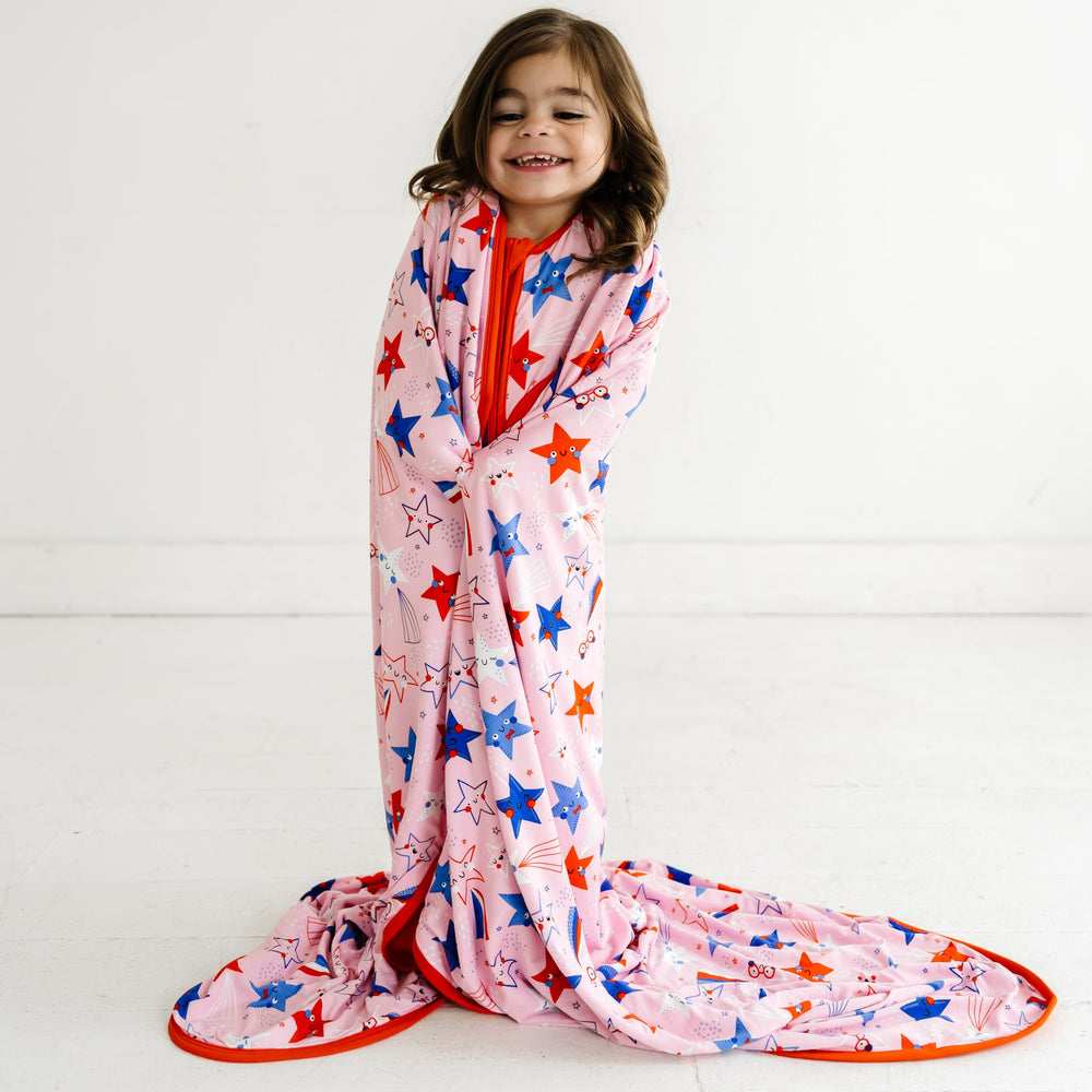 Child wearing a Pink Stars and Stripes Cloud Blanket on her shoulders